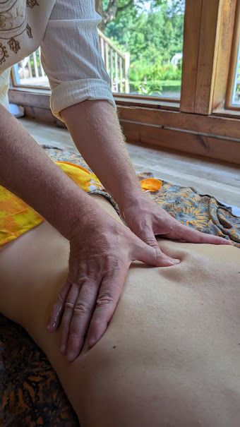 Close view of Sergio's hand on a client's lower back, with a yellow sarong over her legs
